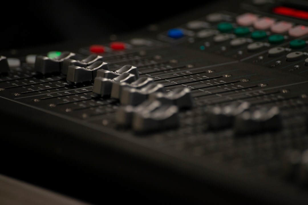Close-up of an audio mixing board with sliders and buttons